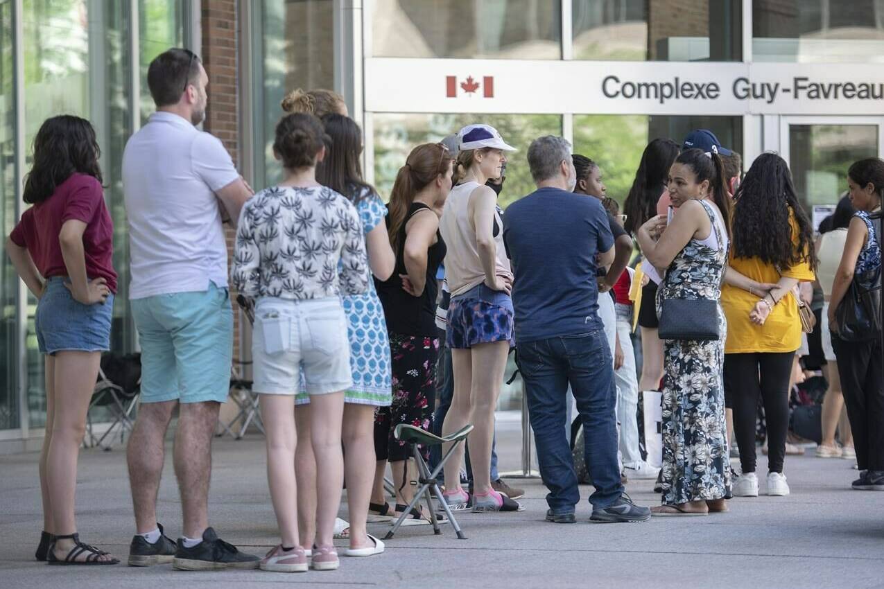 The federal government is adding new passport service locations across Canada as a loud backlash over long wait times continues. People line up outside the Guy Favreau federal building while waiting to apply for a passport in Montreal, Sunday, June 26, 2022. THE CANADIAN PRESS/Graham Hughes