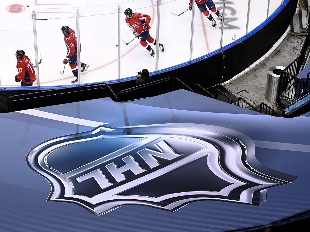 FILE - In this Aug. 14, 2020, file photo, an NHL logo is displayed as Washington Capitals players skate prior to NHL Eastern Conference Stanley Cup playoff hockey game against the New York Islanders in Toronto. (Nathan Denette/The Canadian Press via AP)