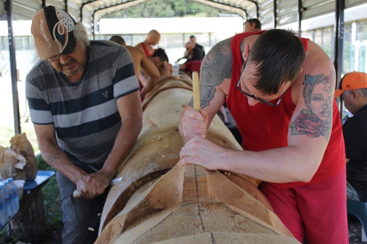 Master carver Tom LaFortune (left) and Vancouver Island Regional Correctional Centre inmate Brandon Castle work on the eagle atop the totem pole. (Austin Westphal/News Staff)