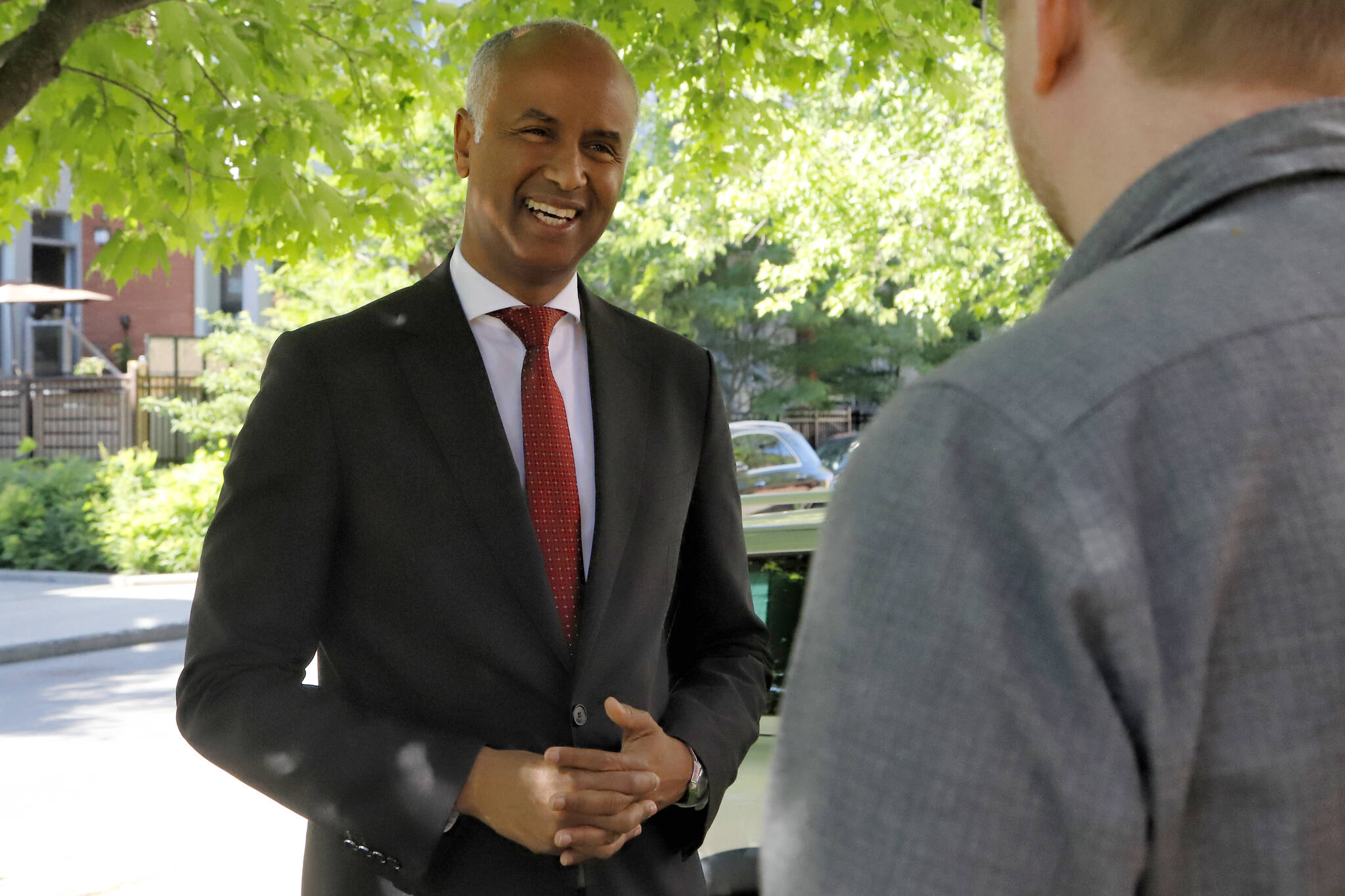 Minister of Housing and Diversity and Inclusion Ahmed Hussen speaks with a home owner after making a green housing announcement in an Ottawa neighborhood on Friday, June 17, 2022. THE CANADIAN PRESS/ Patrick Doyle