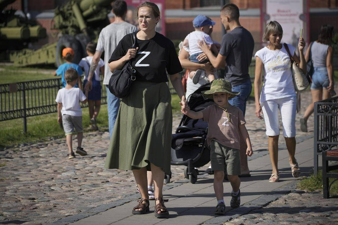 FILE - A woman and her child wearing t-shirts with letter Z, which has become a symbol of the Russian military walk in the Artillery museum in St. Petersburg, Russia, Saturday, Aug. 20, 2022. Six months after Russia sent troops into Ukraine, there’s little sign of the conflict on Moscow’s streets and the capital’s residents seem unconcerned about the economic and political sanctions by Western countries. (AP Photo/Dmitri Lovetsky, File)