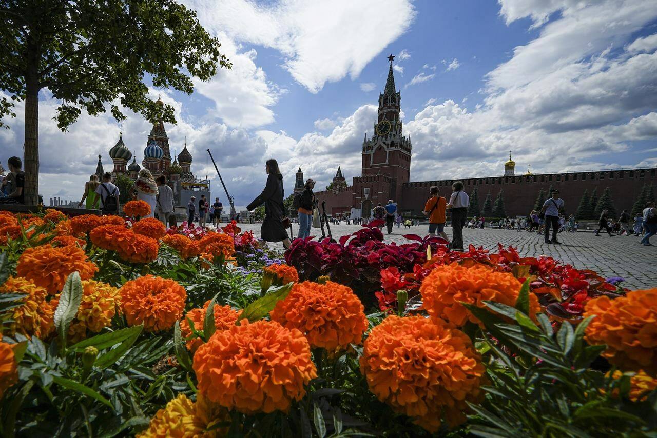 FILE - People walk past flowers during an annual flower festival in Red Square in Moscow, Russia, July 22, 2022. Six months after Russia sent troops into Ukraine, there’s little sign of the conflict on Moscow’s streets and the capital’s residents seem unconcerned about the economic and political sanctions by Western countries. (AP Photo/Alexander Zemlianichenko, File)