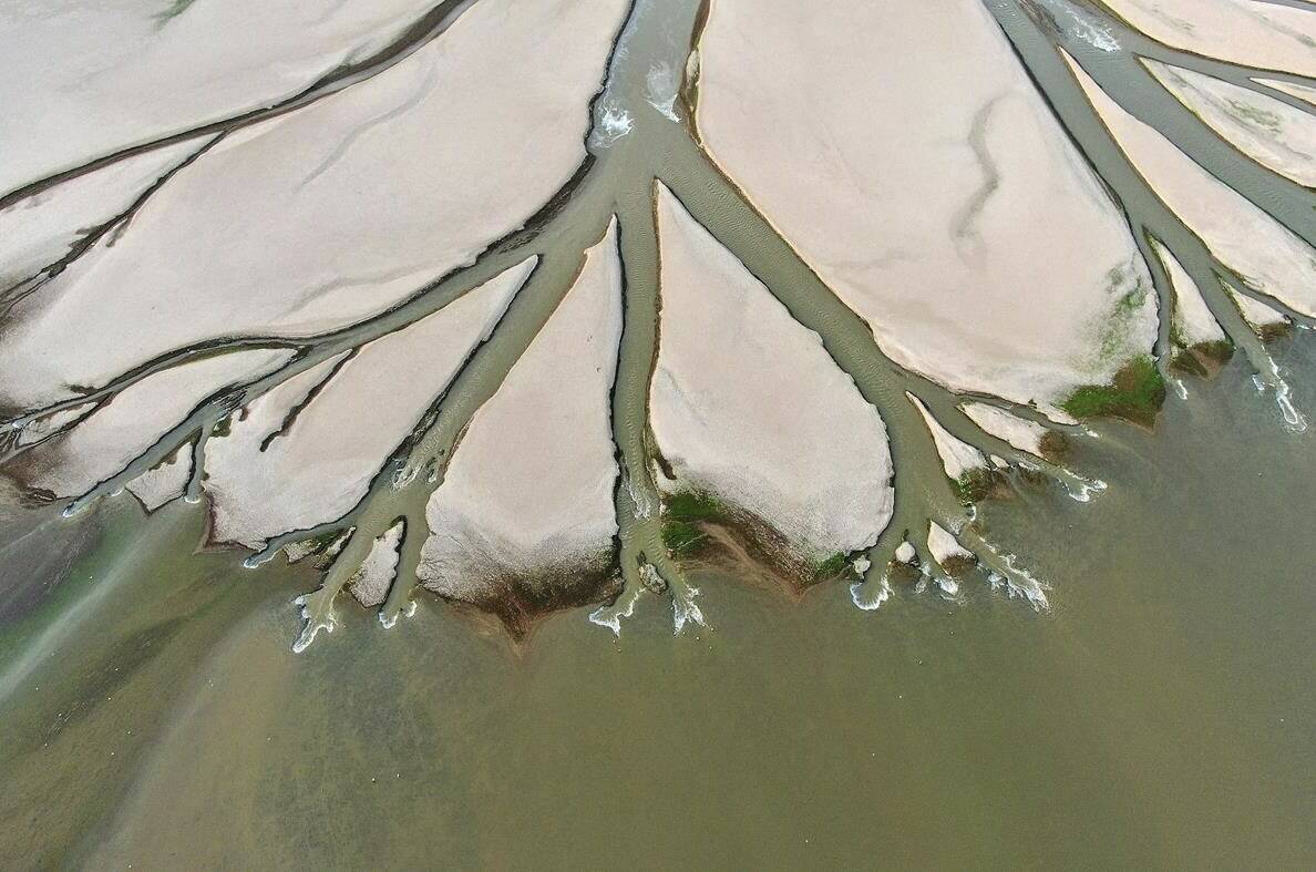 In this aerial photo released by China’s Xinhua News Agency, water flows through chanels in the lake bed of Poyang Lake, China’s largest freshwater lake, in eastern China’s Jiangxi Province, Monday, Aug. 22, 2022. With China’s biggest freshwater lake dried to historic lows by drought, work crews are digging trenches to keep water flowing to irrigate crops. (Wan Xiang/Xinhua via AP)