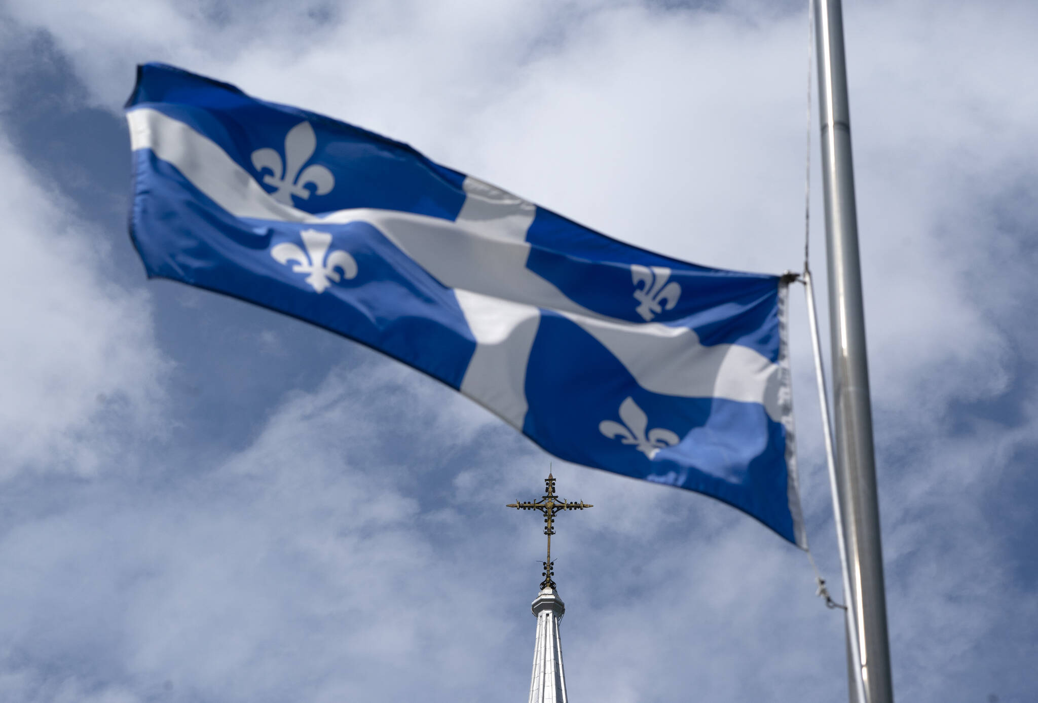 The Quebec flag flies on a flag pole near a church, Tuesday, August 16, 2022 in Gatineau, Que. THE CANADIAN PRESS/Adrian Wyld