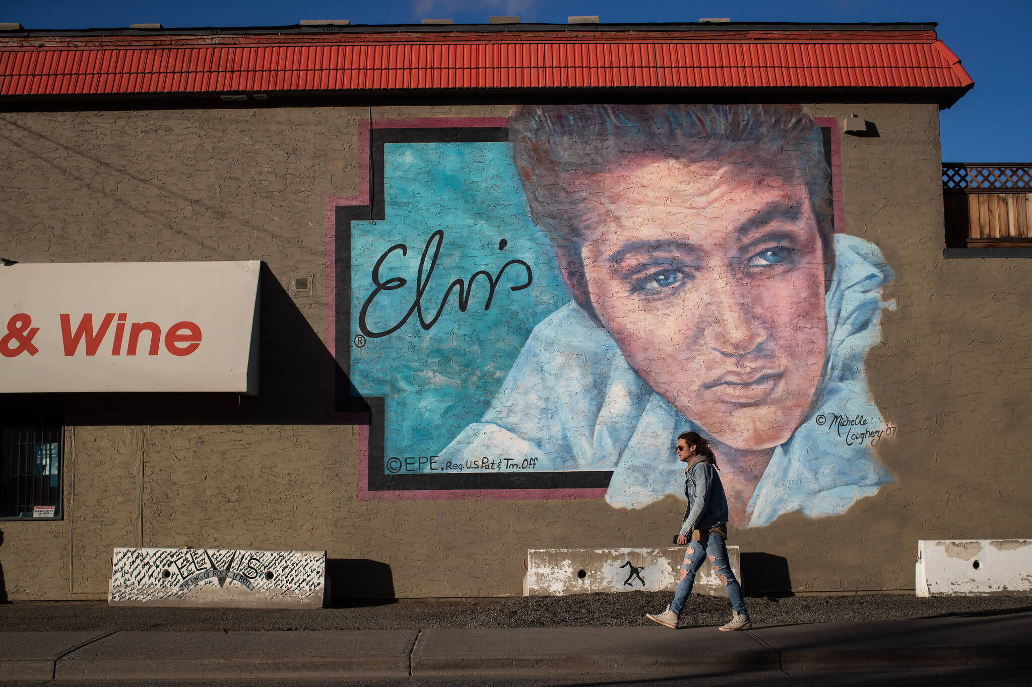 A man walks past a mural of Elvis Presley on the outside of a liquor store, in Merritt, B.C., on Wednesday, March 23, 2022. THE CANADIAN PRESS/Darryl Dyck