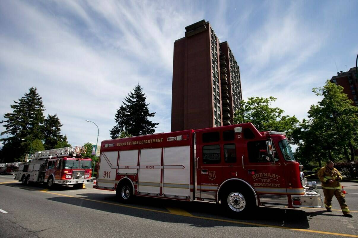 A firefighter returns to a truck after crews extinguished a 3-alarm fire at an apartment building in Burnaby, B.C., on Tuesday May 27, 2014. The union that represents E-Comm 911 emergency service dispatchers in British Columbia is calling for the agency to extend temporary compensation and psychological supports amid a “dire” staffing shortage.THE CANADIAN PRESS/Darryl Dyck