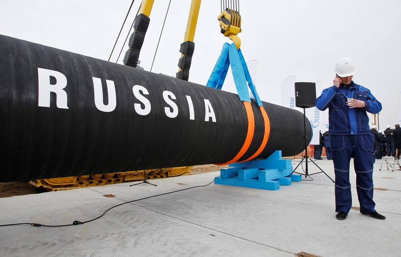 FILE - A Russian construction worker speaks on a mobile phone during a ceremony marking the start of Nord Stream pipeline construction in Portovaya Bay some 170 kms (106 miles) north-west from St. Petersburg, Russia on April 9, 2010. Russian energy giant Gazprom said Friday, Sept. 2, 2022 that it can’t resume the supply of natural gas through a key pipeline to Germany for now because of what it said was a need for urgent maintenance work, just hours before it was due to recommence deliveries. Gazprom said it had identified oil leaks from four turbines at the Portovaya compressor station at the Russian end of the pipeline, including the sole operational one. (AP Photo/Dmitry Lovetsky, File)