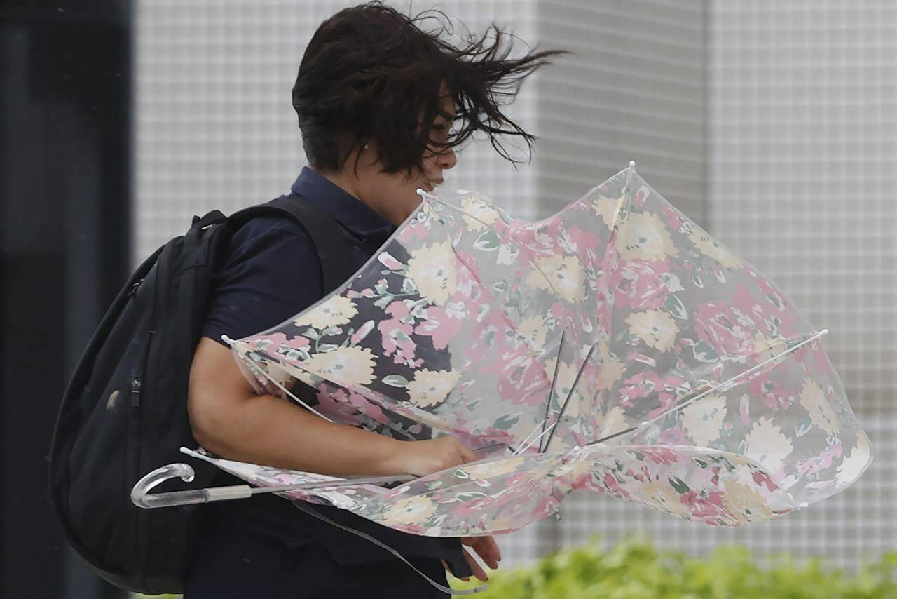 A person braves the strong wind caused by Typhoon Hinnamnor in Naha, Okinawa prefecture, Japan Sunday, Sept. 4, 2022. (Kyodo News via AP)