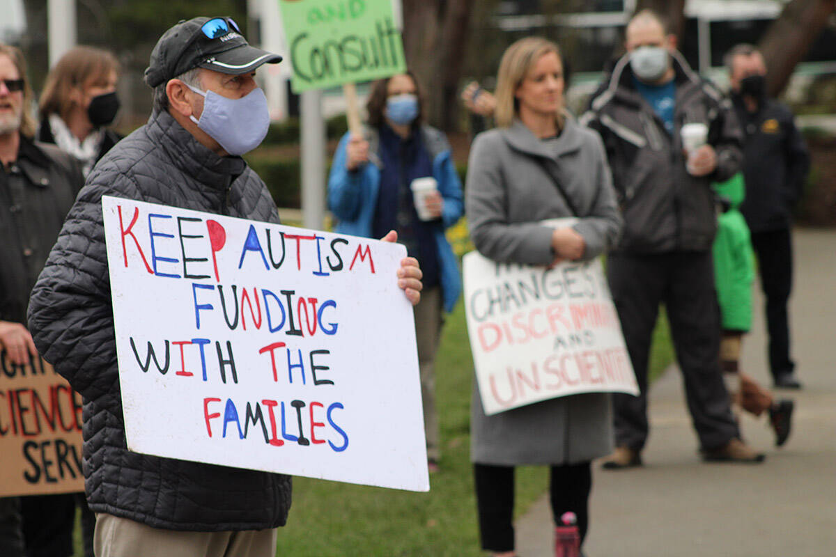 Participants at an event outside the B.C. legislature on Feb. 9 that called for the province to end its planned phase-out of individualized autism funding. (Jake Romphf/News Staff)