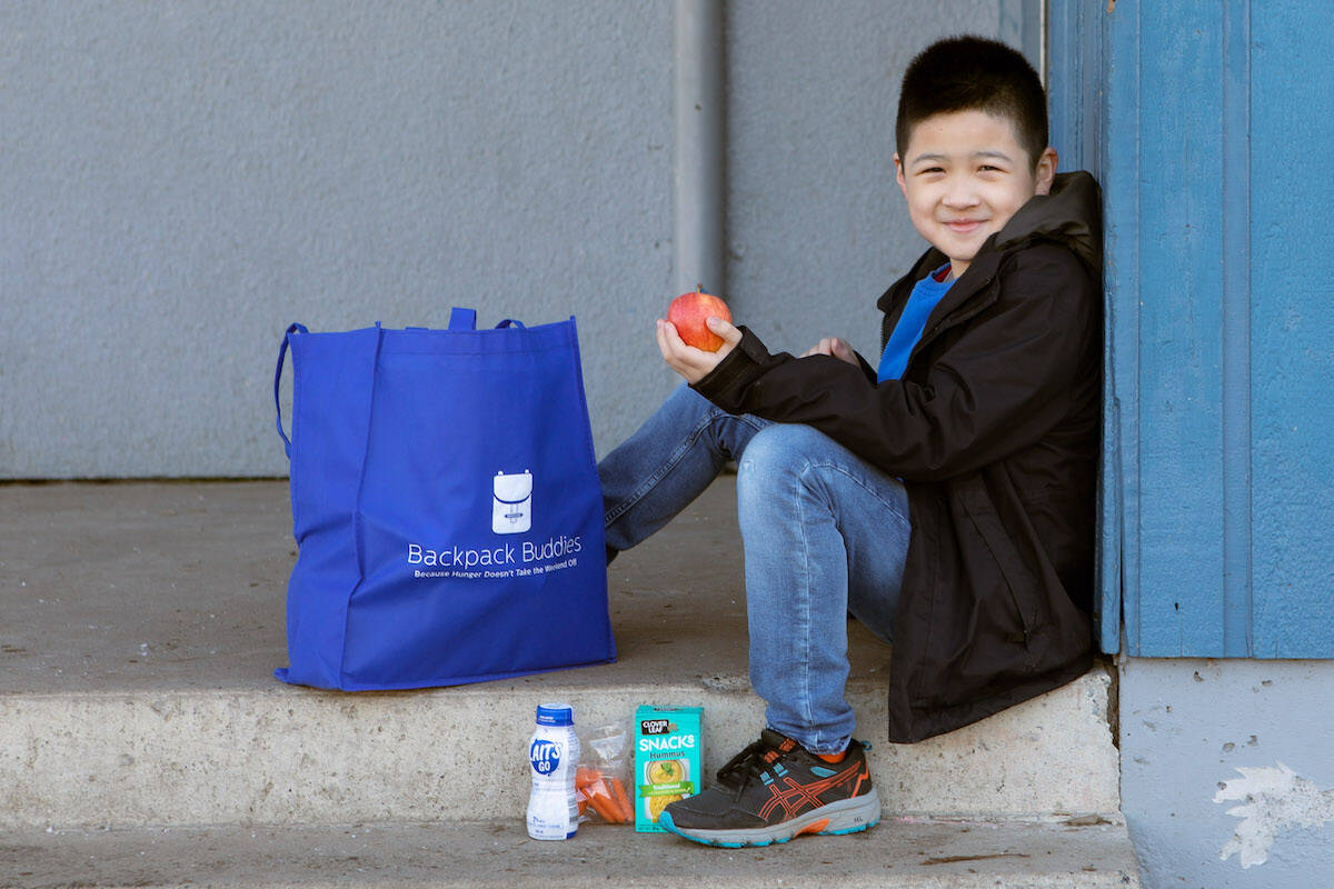 A child poses for a photo with a Backpack Buddies bag of food. (Submitted by Backpackbuddies.ca)