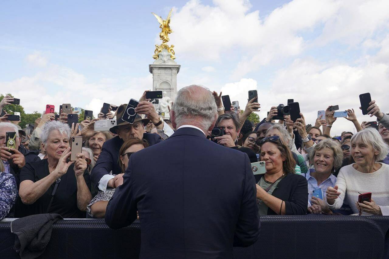 Britain’s King Charles III, back to camera, greets well-wishers as he walks by the gates of Buckingham Palace following Thursday’s death of Queen Elizabeth II, in London, Friday, Sept. 9, 2022. King Charles III, who spent much of his 73 years preparing for the role, planned to meet with the prime minister and address a nation grieving the only British monarch most of the world had known. He takes the throne in an era of uncertainty for both his country and the monarchy itself. (Yui Mok/Pool Photo via AP)
