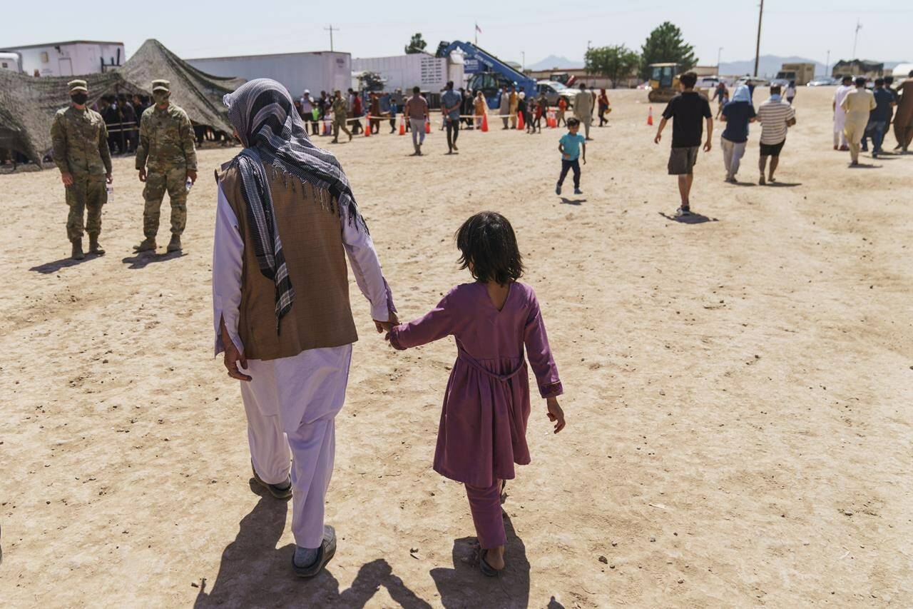 FILE - A man walks with a child through Fort Bliss' Dona Ana Village where Afghan refugees are being housed, in New Mexico, Sept. 10, 2021. President Joe Biden will mark the 21st anniversary of the Sept. 11 attacks at the Pentagon on Sunday, Sept. 11, 2022. Sunday's somber commemoration comes a little more than a year after the Democratic president ended the war in Afghanistan that was launched by the U.S. and allies in response to the terror attacks. (AP Photo/David Goldman, File)