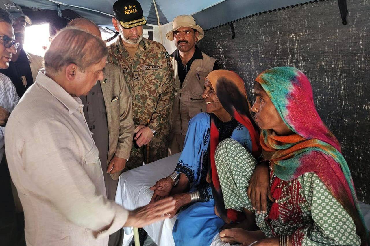 In this handout photo released by Press Information Department, Prime Minister Shahbaz Sharif, left, talks to women inside a tent in the flood-hit area of Suhbatpur in Baluchistan, Pakistan. Sharif on Wednesday promised the country’s millions of homeless people that the government will ensure they are paid to rebuild their homes and return to their lives after the country’s worst-ever floods. (Press Information Department via AP)