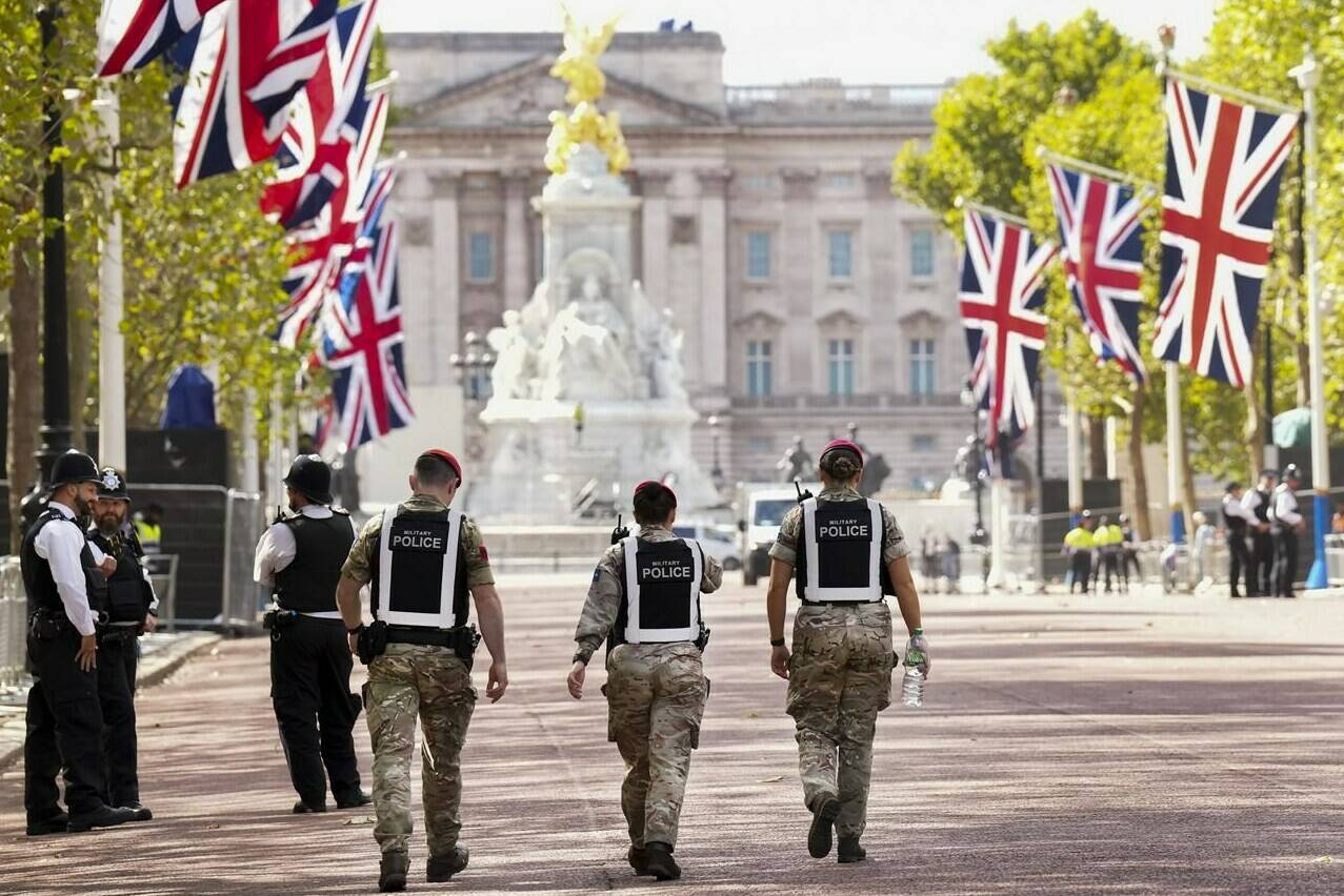 Civilian and Military Police walk the perimeter at the gates of Buckingham Palace in London, Friday, Sept. 16, 2022. Queen Elizabeth, Britain’s longest-reigning monarch and a rock of stability across much of a turbulent century, died Thursday Sept. 8, 2022, after 70 years on the throne. She was 96. THE CANADIAN PRESS/Nathan Denette