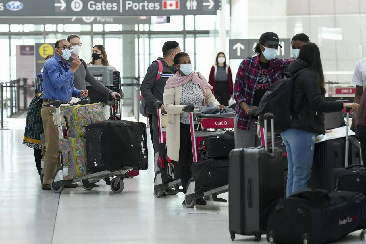 People wait in line to check in at Pearson International Airport in Toronto on Thursday, May 12, 2022. The federal Liberal cabinet is considering whether to renew COVID-19 vaccine mandates and mandatory random testing. THE CANADIAN PRESS/Nathan Denette