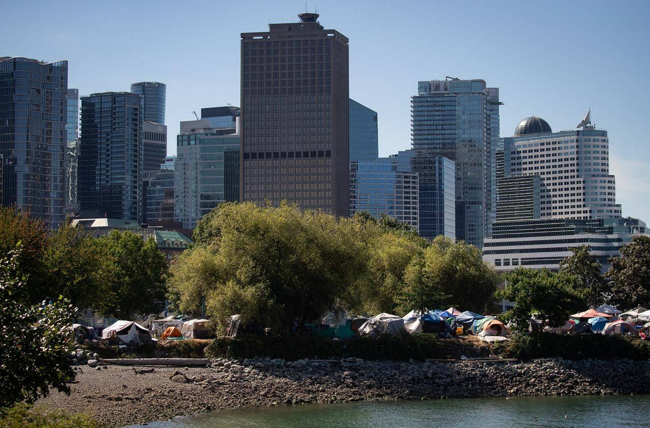 Tents are seen at a homeless encampment at Crab Park as the downtown skyline rises behind them in Vancouver, on Sunday, August 14, 2022. Housing anxiety in British Columbia encompasses young professionals who can’t raise enough cash for down payments, students and low-income families unable to afford rent and people in tents fearful they will die homeless, says Canada’s federal housing advocate. THE CANADIAN PRESS/Darryl Dyck