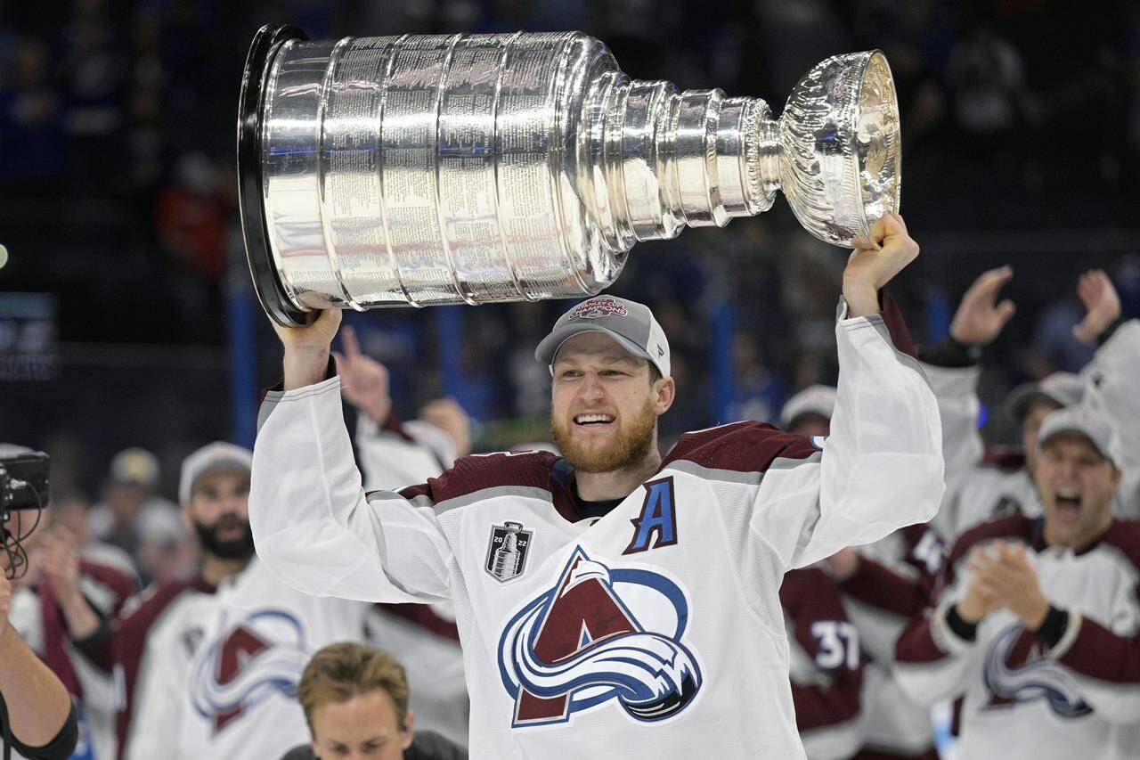 FILE - Colorado Avalanche center Nathan MacKinnon lifts the Stanley Cup after the team defeated the Tampa Bay Lightning in Game 6 of the NHL hockey Stanley Cup Finals on Sunday, June 26, 2022, in Tampa, Fla. The Colorado Avalanche are making Nathan MacKinnon the highest-paid player in the NHL’s salary cap era. MacKinnon, who just turned 27 earlier this month, signed an eight-year contract that is worth $100.8 million, according to a person with knowledge of the situation. The person spoke to The Associated Press on condition of anonymity Tuesday, Sept. 20, 2022, because the team did not announce terms of the contract. (AP Photo/Phelan M. Ebenhack, File)
