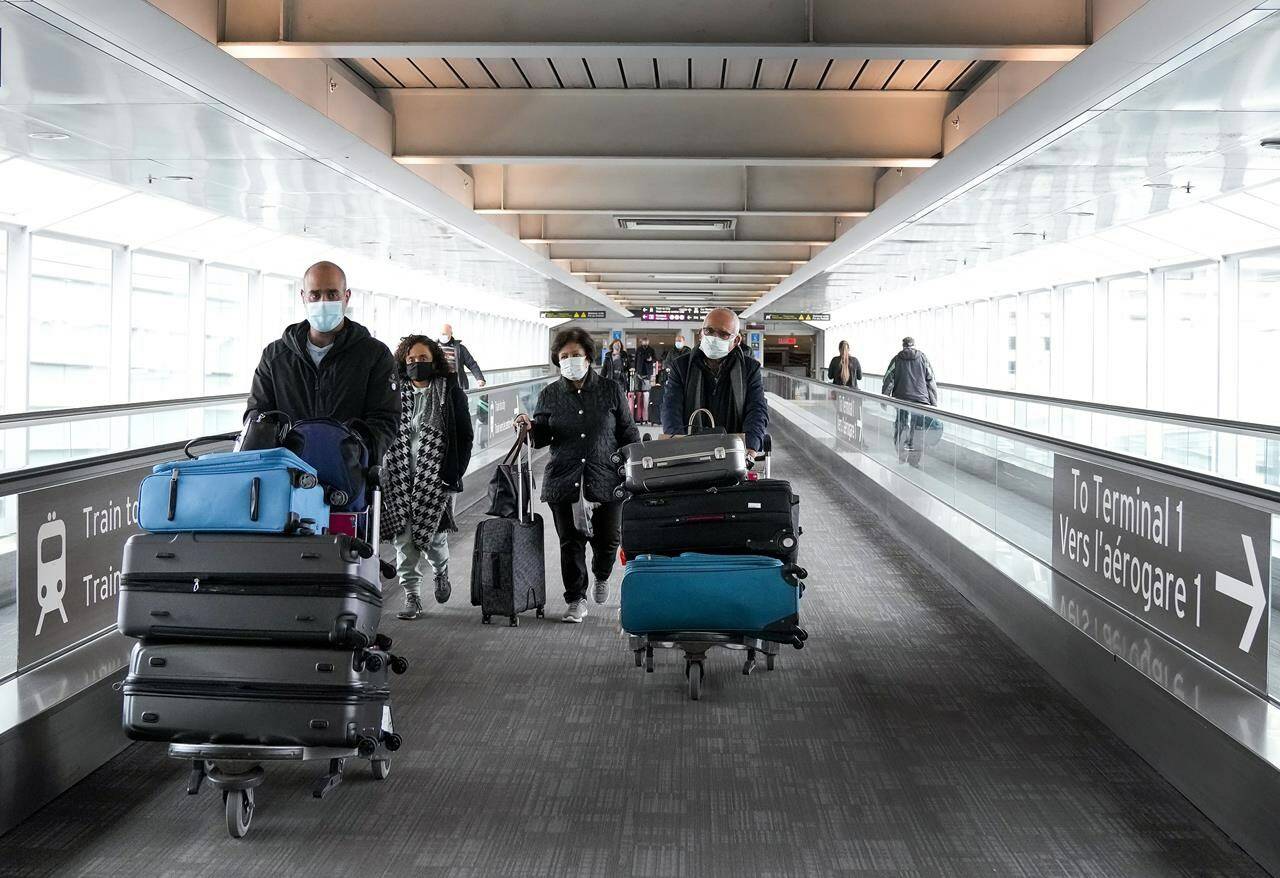 People travel at Pearson International Airport, in Toronto, Friday, Dec. 3, 2021. A cabinet order enforcing mandatory vaccinations at the Canadian border will be allowed to expire at the end of the month.THE CANADIAN PRESS/Nathan Denette