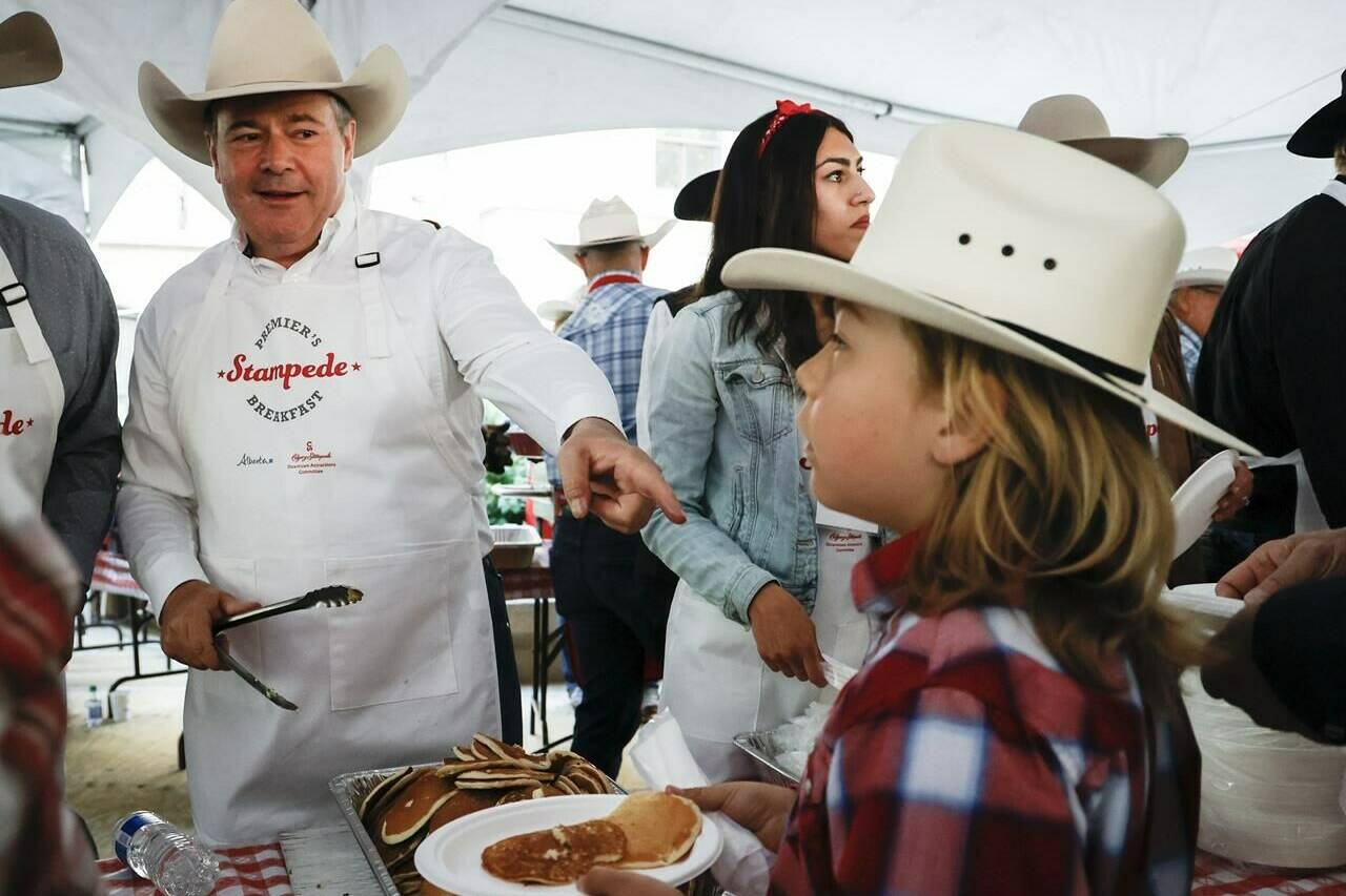 Alberta Premier Jason Kenney, left, dishes out pancakes at his last Premier’s annual Stampede breakfast as premier in Calgary, Alta., Monday, July 11, 2022.THE CANADIAN PRESS/Jeff McIntosh