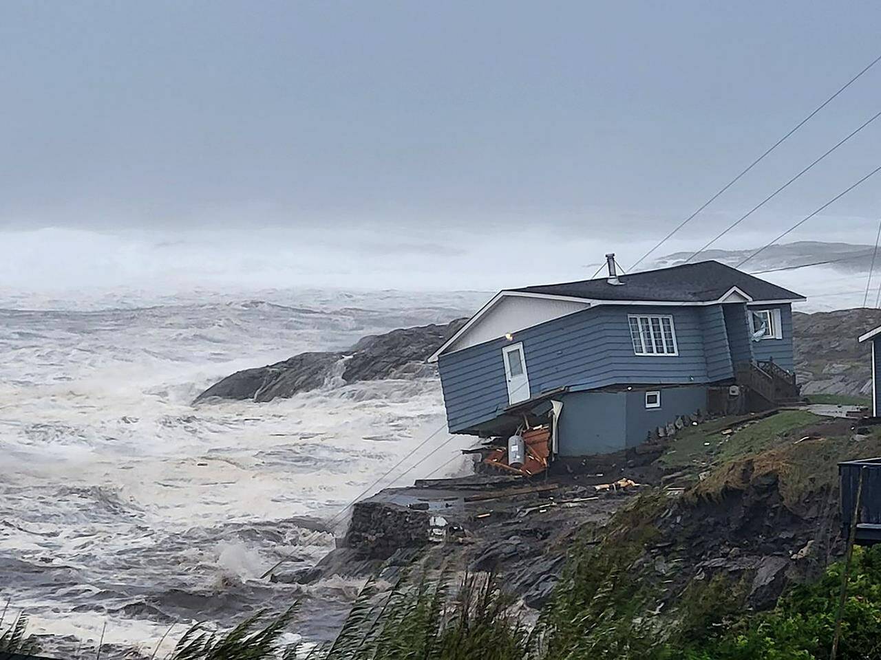 In this photo provided by Wreckhouse Press a home fights against high winds caused by post Tropical Storm Fiona in Port aux Basques, Newfoundland and Labrador, Saturday, Sept. 24, 2022. The home has since been lost at sea. (Rene Roy/Wreckhouse Press via AP)