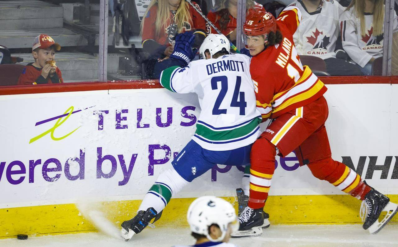 Vancouver Canucks defenceman Travis Dermott, left, checks Calgary Flames forward Sonny Milano during first period NHL pre-season hockey action in Calgary, Alta., Sunday, Sept. 25, 2022. THE CANADIAN PRESS/Jeff McIntosh