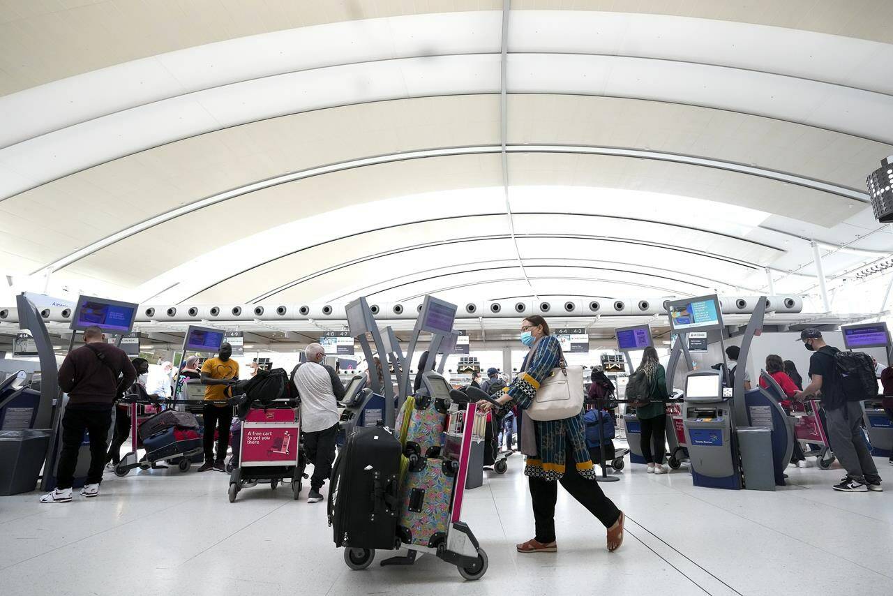 People wait in line to check in at Pearson International Airport in Toronto on Thursday, May 12, 2022. The federal government is expected to officially announce the end of COVID-19 border restriction today with the looming expiry of a cabinet order affecting mandatory vaccinations, testing and quarantine of international travellers. THE CANADIAN PRESS/Nathan Denette