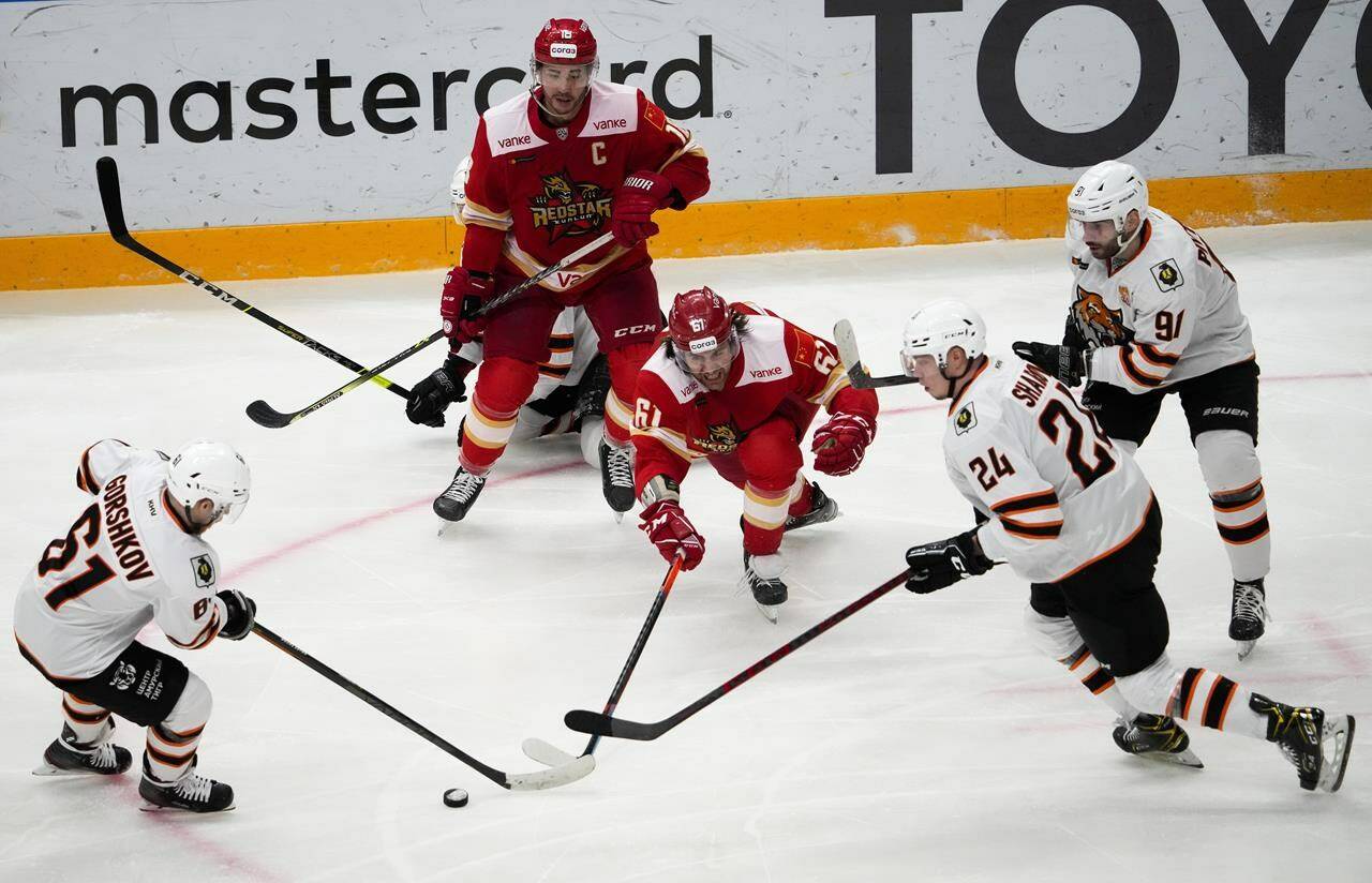 Kunlun Red Star’s Ethan Werek, center, fights for the puck with Amur’s Alexander Gorshkov, left, and Amur’s Alexander Sharov, right, during the Kontinental Hockey League ice hockey match between Kunlun Red Star Beijing and Amur Khabarovsk in Mytishchi, just outside Moscow, Russia, on November 15, 2021. Canadians continue to play hockey for Kontinental Hockey League teams in Russia and Belarus despite the Canadian government’s warning to get out of those countries. THE CANADIAN PRESS/AP, Alexander Zemlianichenko