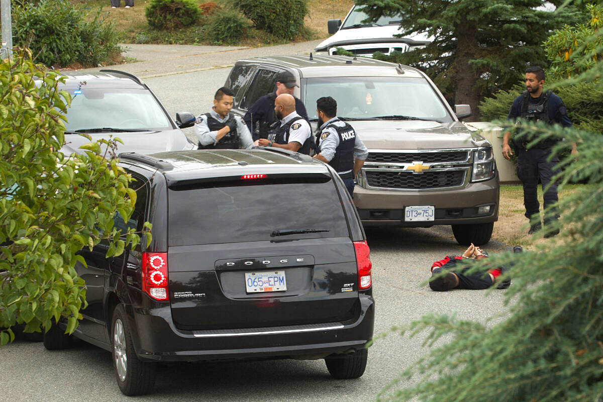 A suspect lies cuffed on the ground after Langley RCMP struck a vehicle during an arrest in the City on Wednesday morning. (Special to the Langley Advance Times)