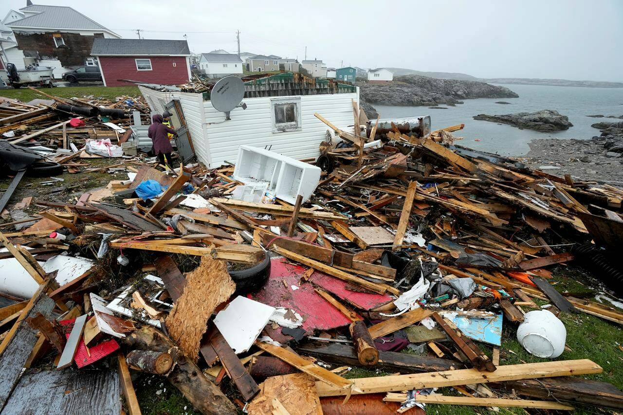 A resident and a search-and-rescue worker examine the destroyed remains of a home in Port aux Basques, N.L., Monday, Sept.26, 2022. Newfoundland and Labrador is earmarking $30 million in financial relief for residents affected by post-tropical storm Fiona. THE CANADIAN PRESS/Frank Gunn