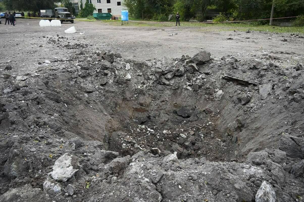 A police officer stands next to a crater created by an explosion after a Russian rocket attack in Zaporizhzhia, Ukraine, Friday, Sept. 30, 2022. A Russian strike on the Ukrainian city of Zaporizhzhia killed at least 23 people and wounded dozens, an official said Friday. Vladimir Putin’s claim to parts of Ukraine is little more than “political theatre” with “no legitimacy,” Canada and the United States declared Friday, and should have no impact on how best to deploy military aid from the West. THE CANADIAN PRESS/AP/Efrem Lukatsky