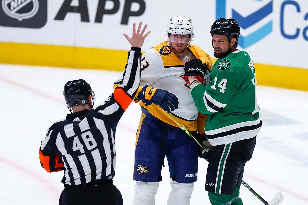 Nashville Predators forward Yakov Trenin (13) and Dallas Stars forward Jamie Benn (14) react after being called for penalties by referee Garrett Rank (48) during the first period of an NHL hockey game, Wednesday, Feb. 9, 2022, in Dallas. (AP Photo/Brandon Wade)