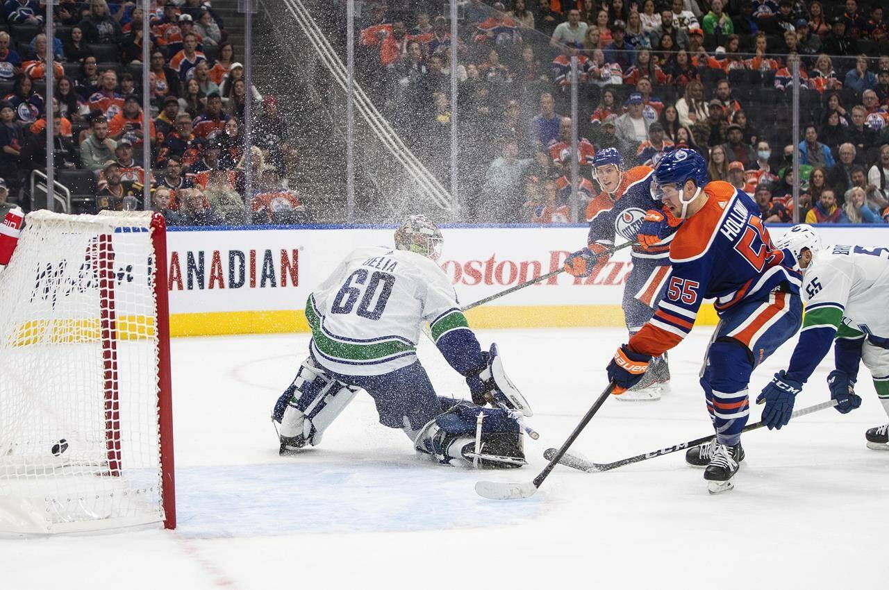 Vancouver Canucks goalie Collin Delia (60) is scored on by Edmonton Oilers’ Tyson Barrie (22) as Dylan Holloway (55) watches the puck go in the net during second period preseason action in Edmonton on Monday, October 3, 2022.THE CANADIAN PRESS/Jason Franson