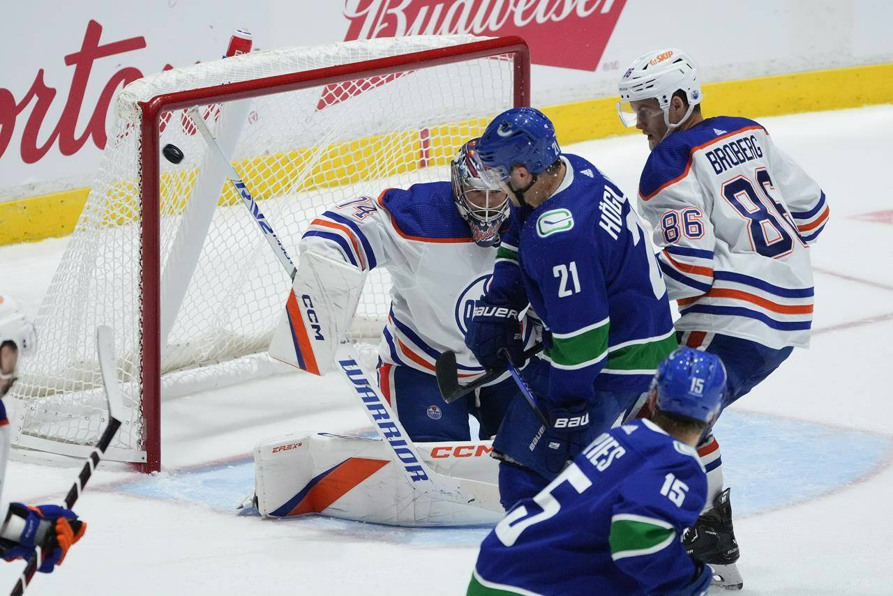 Vancouver Canucks’ Nils Hoglander (21), of Sweden, scores against Edmonton Oilers goalie Stuart Skinner (74) during the first period of a pre-season NHL hockey game in Abbotsford, B.C., on Wednesday, October 5, 2022. THE CANADIAN PRESS/Darryl Dyck