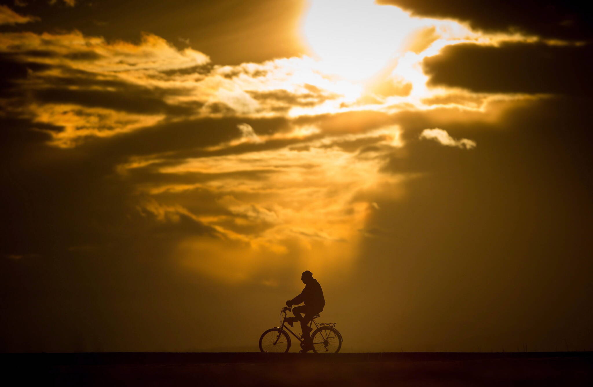 A man is silhouetted while riding a bike at Garry Point Park at sunset in Richmond, B.C., on Monday, February 27, 2017. THE CANADIAN PRESS/Darryl Dyck