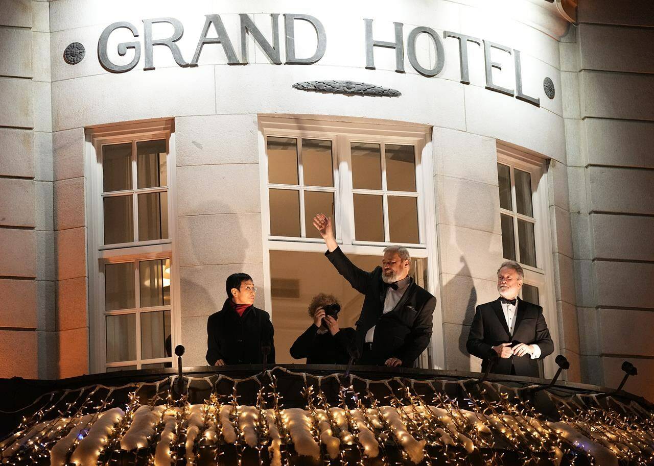 FILE- David Beasley, right, the head of the World Food Program (WFP), which was awarded the Nobel Peace Prize for 2020 and 2021 Nobel Peace Prize winners Dmitry Muratov, center, from Russia and Maria Ressa of the Philippines react as they stand on the balcony of the Grand Hotel in Oslo, Norway, Friday, Dec. 10, 2021. For the two journalists who won the Nobel Peace Prize in 2021, the past year has not been easy. Dmitry Muratov of Russia and Maria Ressa of the Philippines have been fighting for the survival of their news organizations, defying government efforts to silence them. (AP Photo/Alexander Zemlianichenko, File)