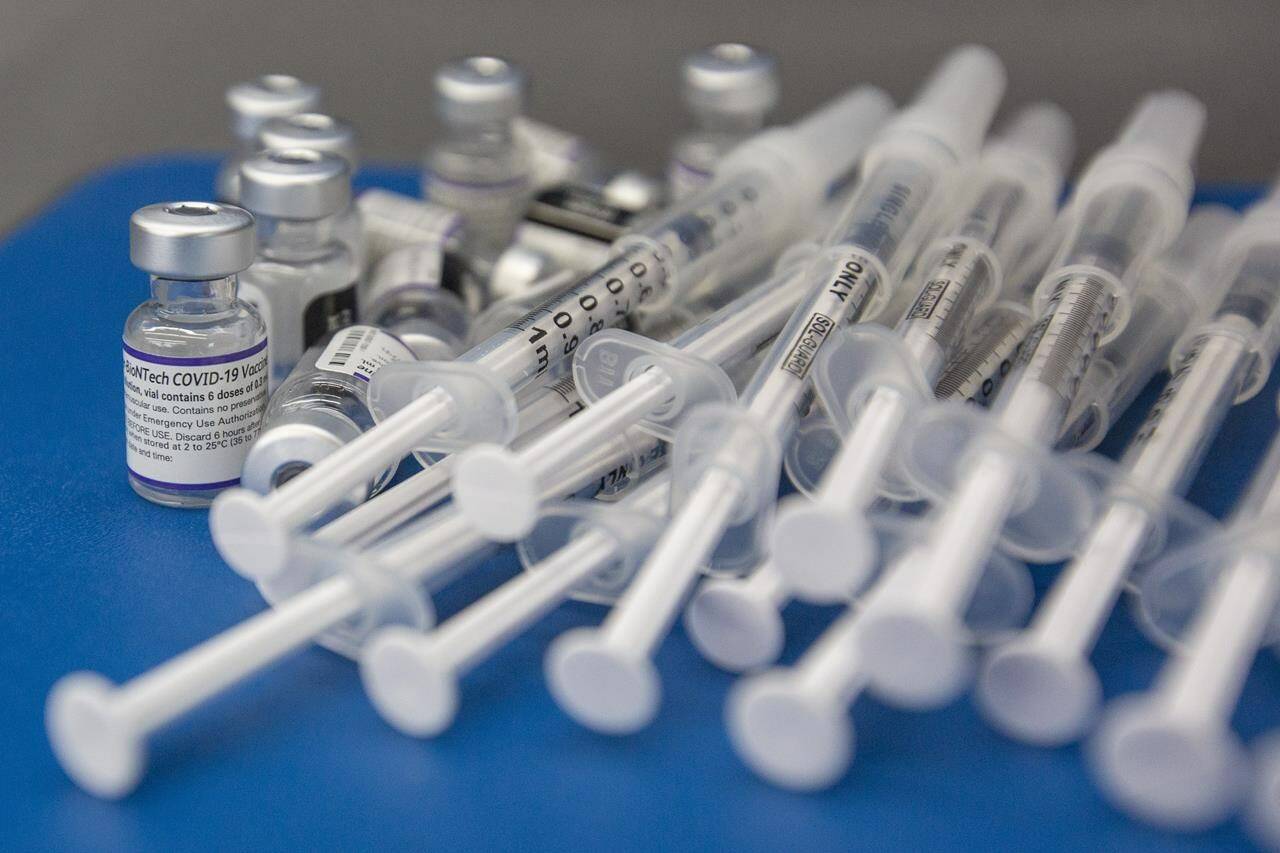 Syringes and vials of Pfizer-BioNTech COVID-19 vaccine are seen on a work surface in Kingston, Ont., Saturday, Dec. 18, 2021. Health Canada says Canadians can now be given the Pfizer-BioNTech COVID-19 booster vaccine that targets the BA.4 and BA.5 strains of the Omicron variant. THE CANADIAN PRESS/Lars Hagberg