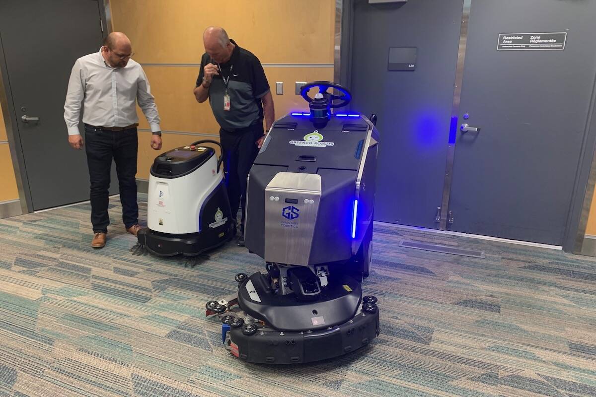 Ionut Bordieanu (left) with Greenco Robots and Neil Janssen with Bouygues double check the new cleaning robots at Kelowna International Airport before sending them off on their duties (Brittany Webster - Capital News)