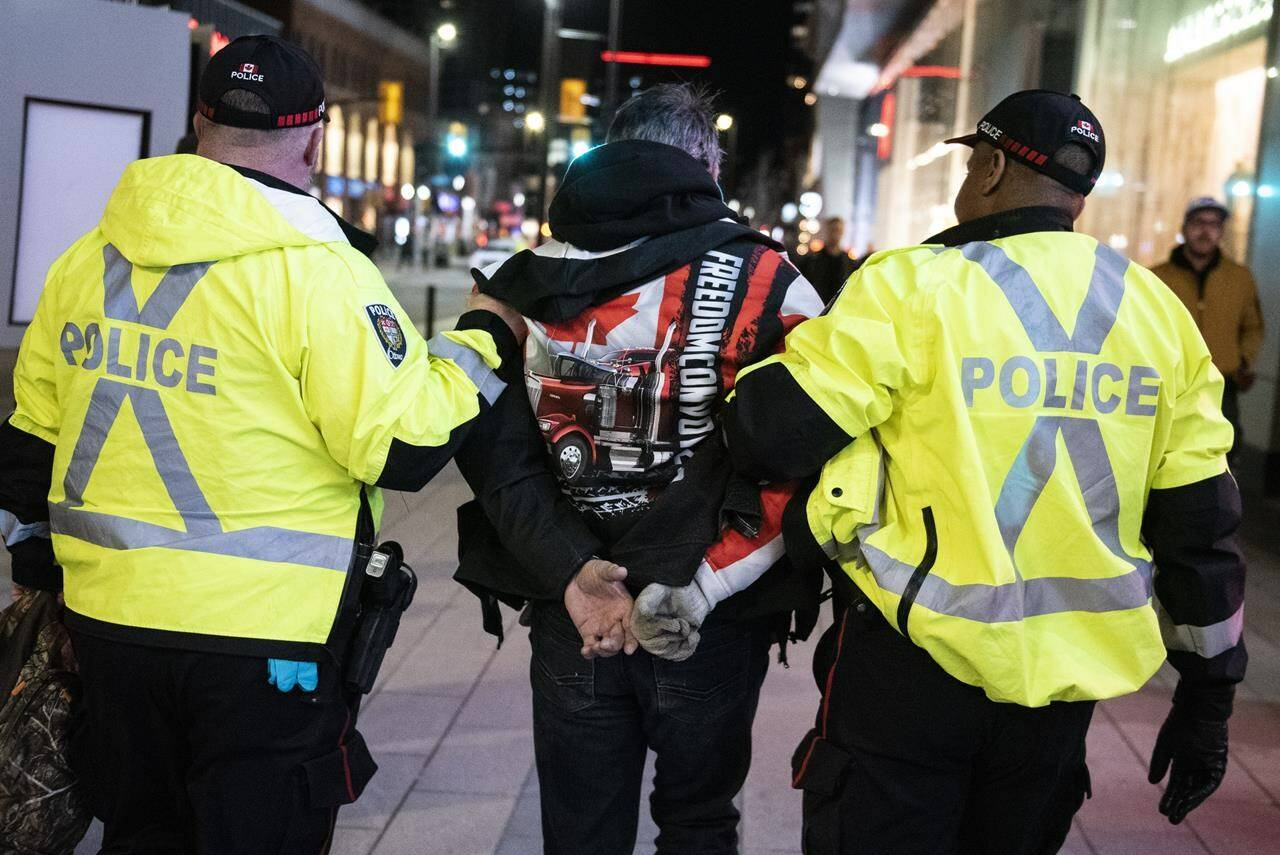 Police take a person into custody as they worked to clear an area on Rideau Street, during a convoy-style protest participants are calling “Rolling Thunder,” in Ottawa, on Friday, April 29, 2022. The public inquiry into the federal government’s unprecedented use of the Emergencies Act during what organizers called “Freedom Convoy” protests last winter begins on Thursday and 65 witnesses, including Prime Minister Justin Trudeau and high profile convoy organizers, are expected to testify. THE CANADIAN PRESS/Justin Tang