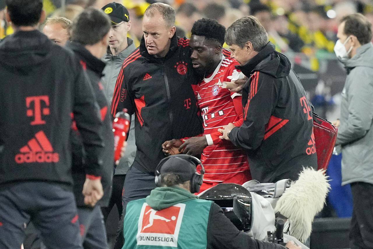 Bayern’s Alphonso Davies, centre, leaves the field after getting injured during the German Bundesliga soccer match between Borussia Dortmund and Bayern Munich in Dortmund, Germany, Saturday, Oct. 8, 2022. Davies, who had to be helped off the field after taking a boot to the head, was back training Friday with Bayern Munich. THE CANADIAN PRESS/AP-Martin Meissner