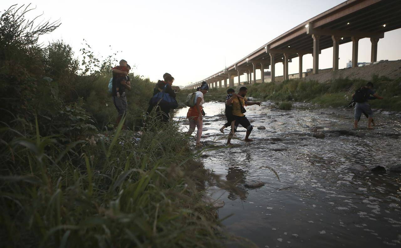 FILE - Venezuelan migrants walk across the Rio Bravo towards the United States border to surrender to the border patrol, from Ciudad Juarez, Mexico, Oct. 13, 2022. President Joe Biden last week invoked a Trump-era rule known as Title 42, which Biden’s own Justice Department is fighting in court, to deny Venezuelans fleeing their crisis-torn country the chance to request asylum at the border. The rule, first invoked by Trump in 2020, uses emergency public health authority to allow the United States to keep migrants from seeking asylum at the border, based on the need to help prevent the spread of COVID-19. (AP Photo/Christian Chavez, File)