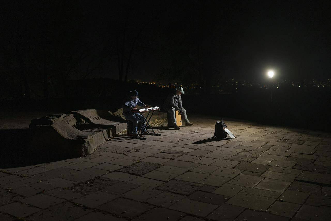 Street musicians play their instruments in a square without electric lights in Kyiv, Ukraine, Tuesday, Oct. 18, 2022. (AP Photo/Emilio Morenatti)