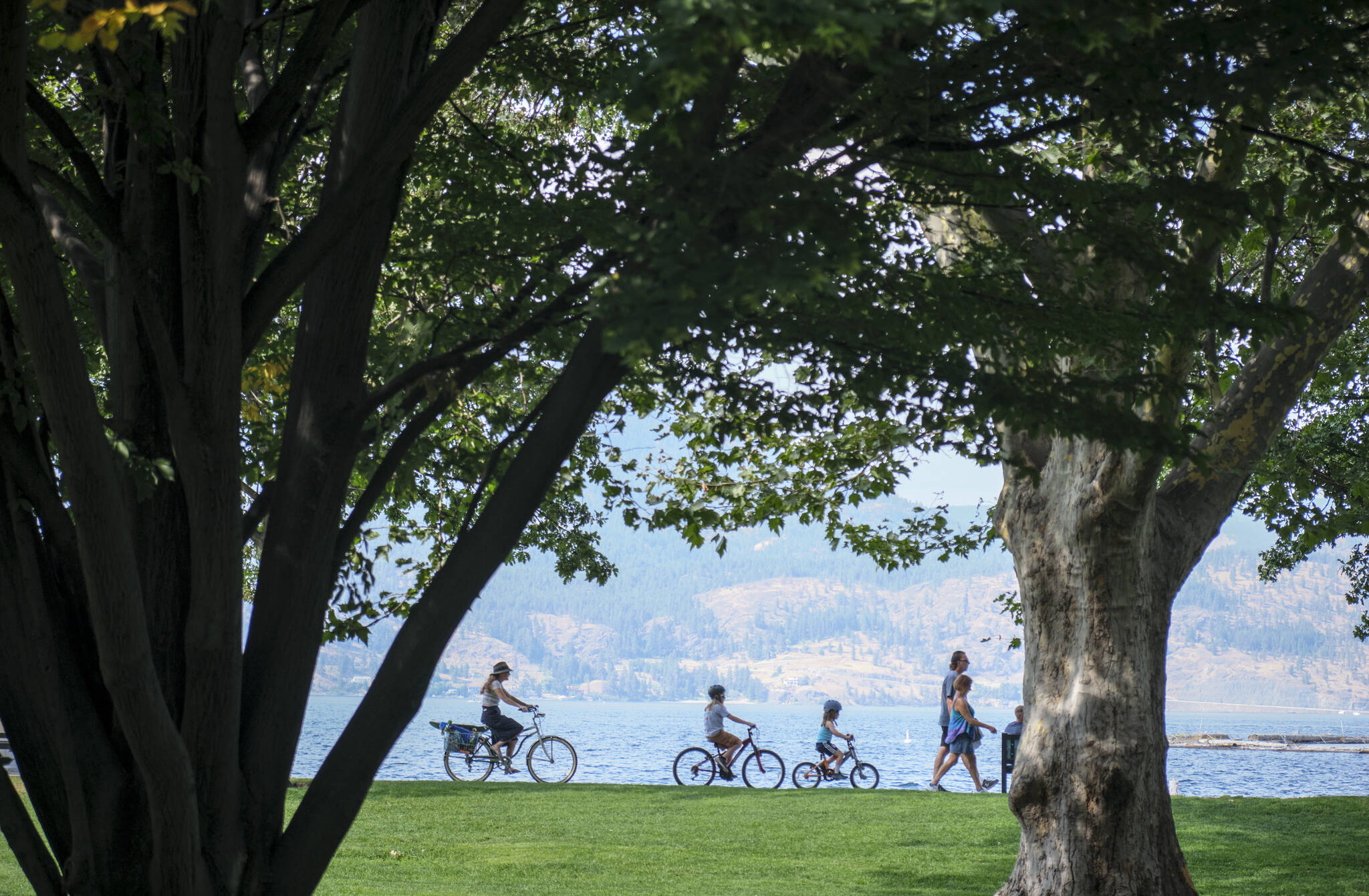 A family cycles along Lake Okanagan in Kelowna, Wednesday, Aug. 31, 2022. Late summer weather has stretched beyond mid-October for much of the province, but that is expected to change this weekend. THE CANADIAN PRESS/Jeff McIntosh