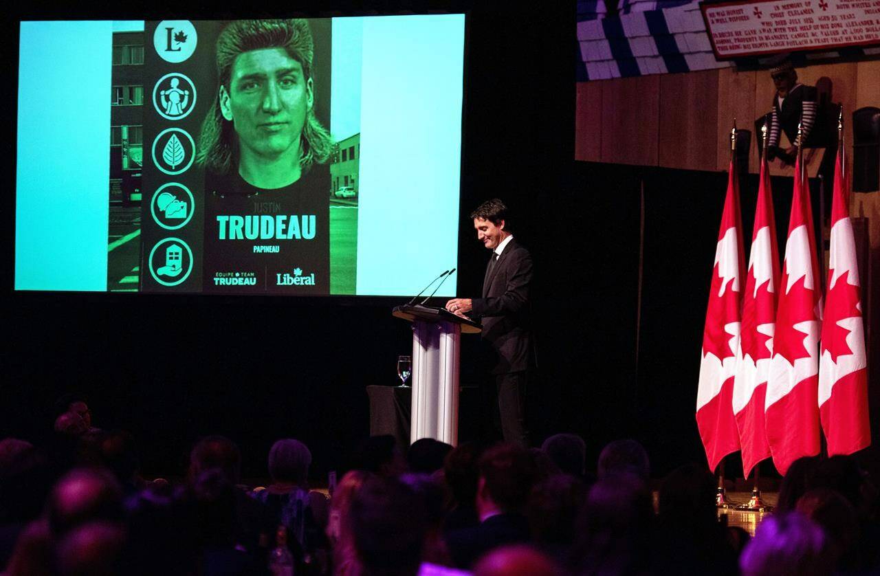 Prime Minister Justin Trudeau references a joke image of himself with a mullet haircut during his speech at the Parliamentary Press Gallery Dinner at the Museum of History in Gatineau, Que., on Saturday, Oct. 22, 2022. THE CANADIAN PRESS/Spencer Colby