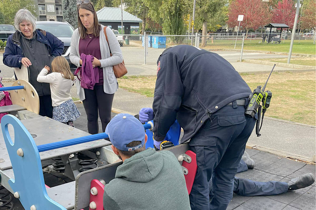 As onlookers watched, a Langley City fire crew took apart a playground teeter-totter to rescue a little girl who had become trapped Sunday morning at Linwood Park. (Special to Langley Advance Times)
