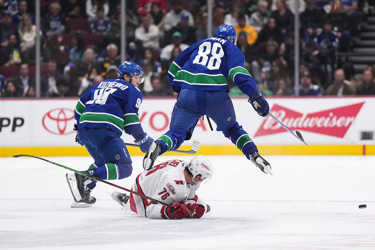 Vancouver Canucks’ Nils Aman (88), of Sweden, leaps over Carolina Hurricanes’ Brady Skjei (76) during second period NHL action in Vancouver on Monday, October 24, 2022. THE CANADIAN PRESS/Darryl Dyck