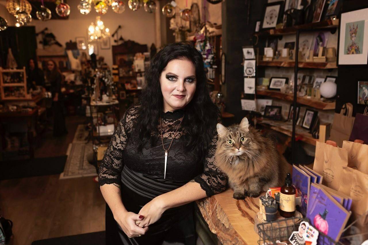 Purely Wicked boutique owner Kim Goodhue and “shop kitty” Minoux are shown in a handout photo. Witches say social media platforms such as TikTok are conjuring a boom for businesses offering magical wares, services and education. Goodhue says her brick-and-mortar witchy boutique in St. Thomas, Ont., welcomes all comers, from practitioners who want to learn more about a particular kind of magic to fans of Harry Potter. THE CANADIAN PRESS/HO-Barb Weir/Purely Wicked **MANDATORY CREDIT**