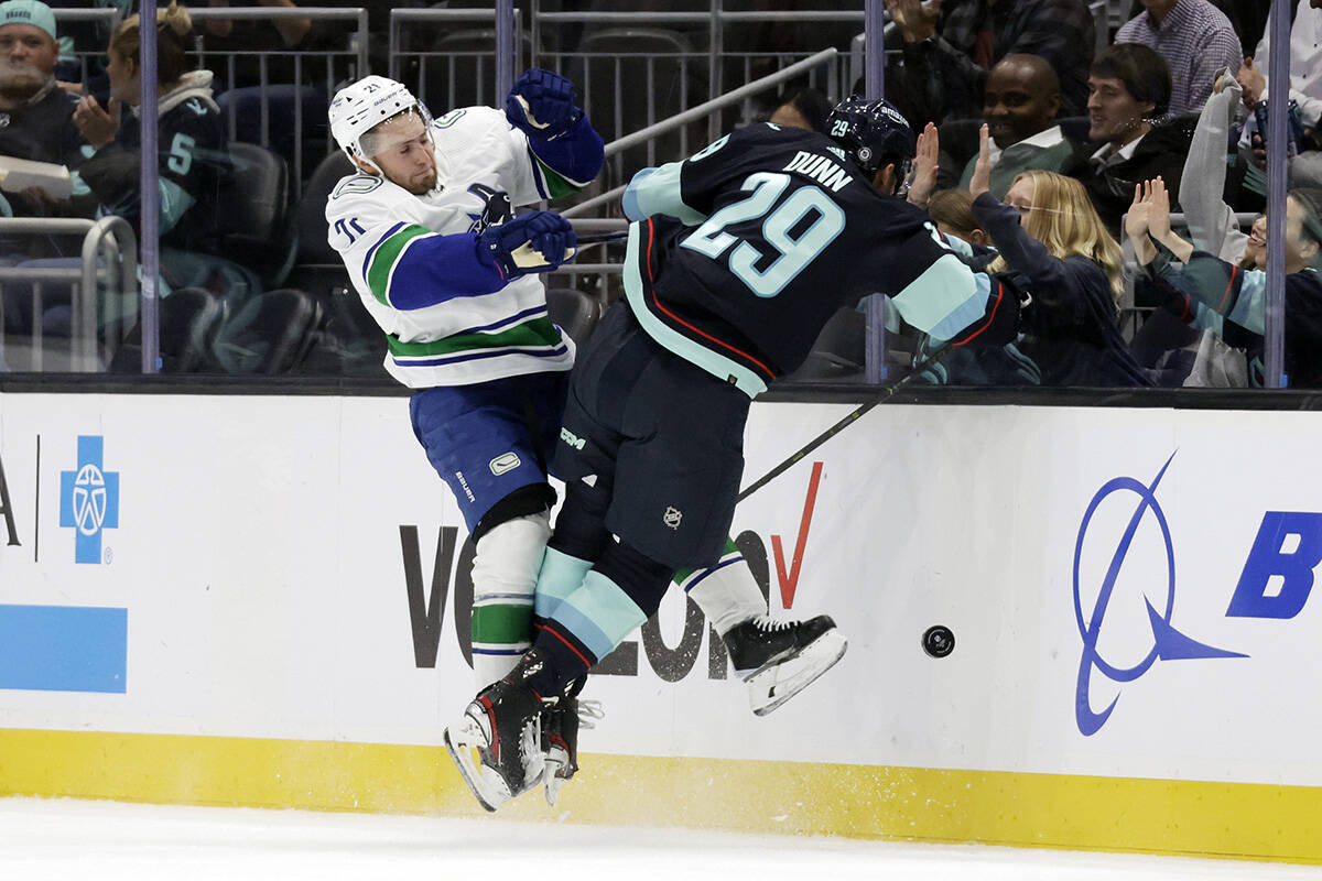 Vancouver Canucks left wing Nils Hoglander (21) collides with Seattle Kraken defenceman Vince Dunn (29) as they battle for the puck during the first period of an NHL hockey game, Thursday, Oct. 27, 2022, in Seattle. (AP Photo/John Froschauer)