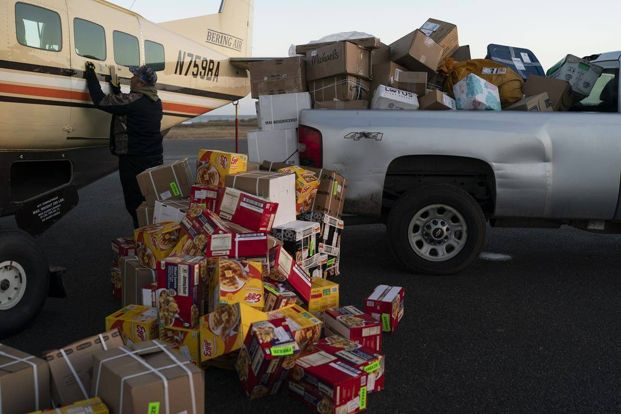 Bering Air agent Denis Sinnok shuts the door of a Cessna plane at the air strip after unloading the dozens of boxes of Eggo waffles and other goods in Shishmaref, Alaska, Thursday, Oct. 6, 2022. (AP Photo/Jae C. Hong)