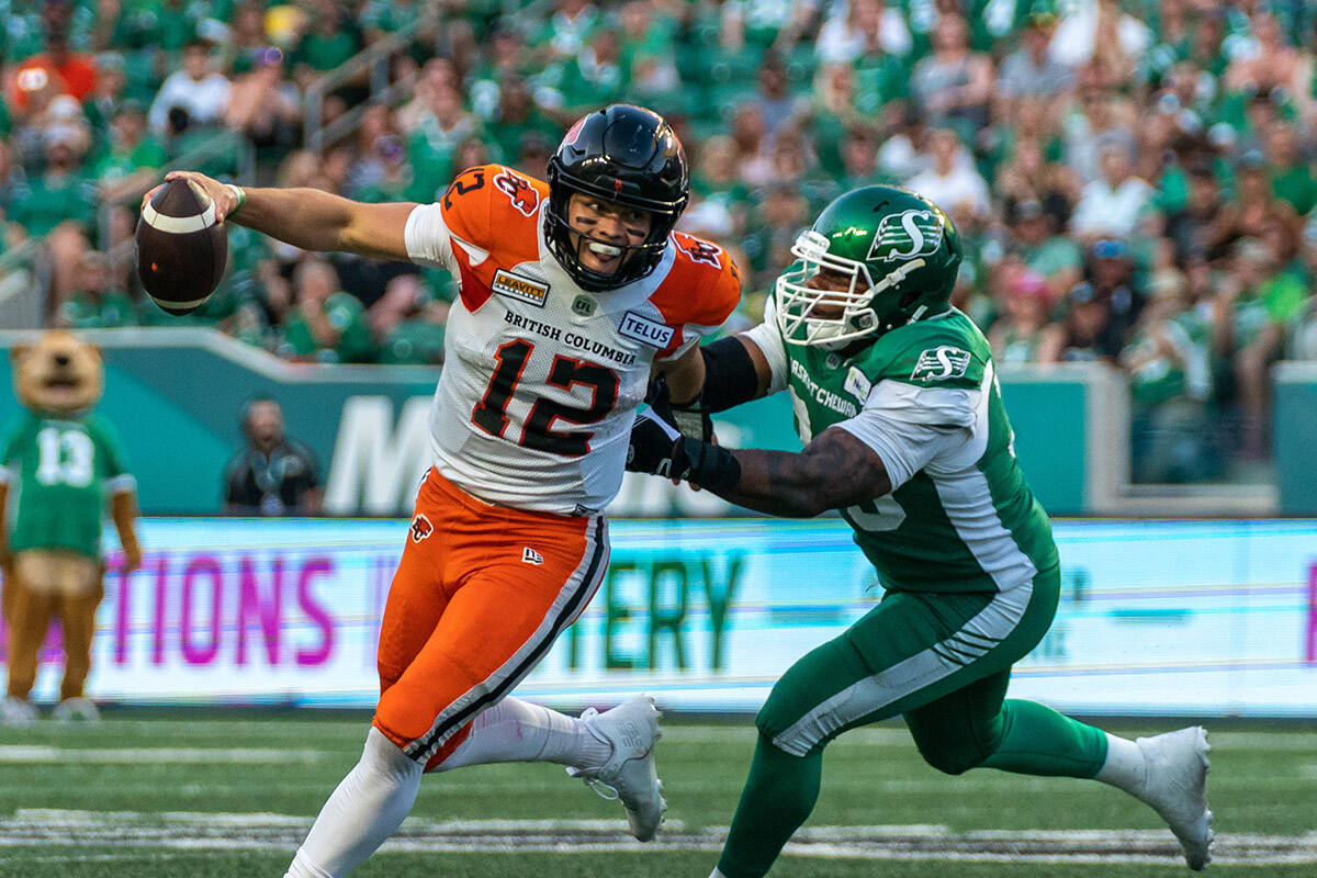 BC Lions quarterback Nathan Rourke (12) evades a tackle from Saskatchewan Roughriders defensive lineman Charleston Hughes (39) during the second quarter of CFL football action in Regina, on Friday, July 29, 2022. THE CANADIAN PRESS/Heywood Yu