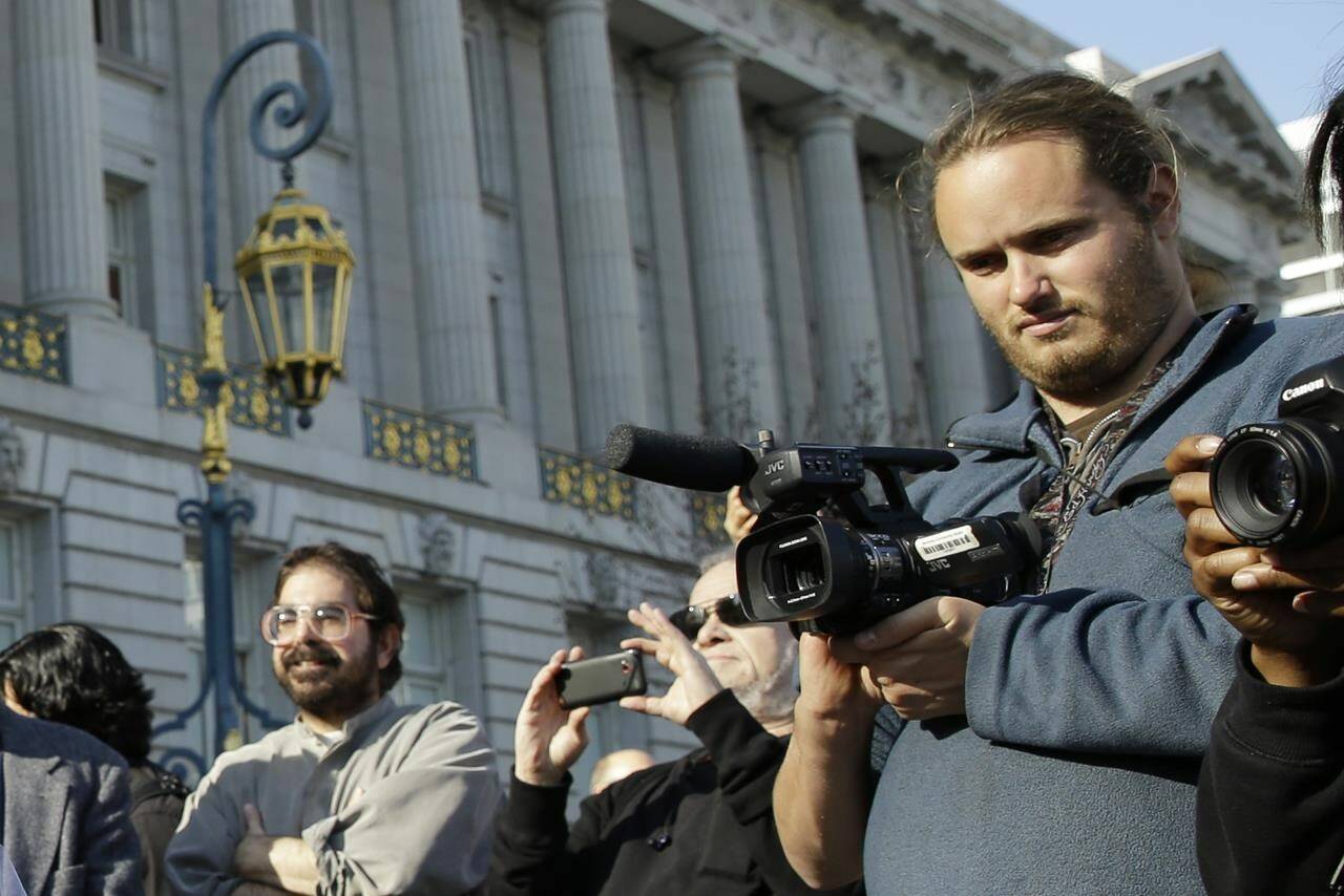 David DePape, right, records the nude wedding of Gypsy Taub outside City Hall on Dec. 19, 2013, in San Francisco. DePape is accused of breaking into House Speaker Nancy Pelosi’s California home and severely beating her husband with a hammer. DePape was known in Berkeley, Calif., as a pro-nudity activist who had picketed naked at protests against local ordinances requiring people to be clothed in public. (AP Photo/Eric Risberg)